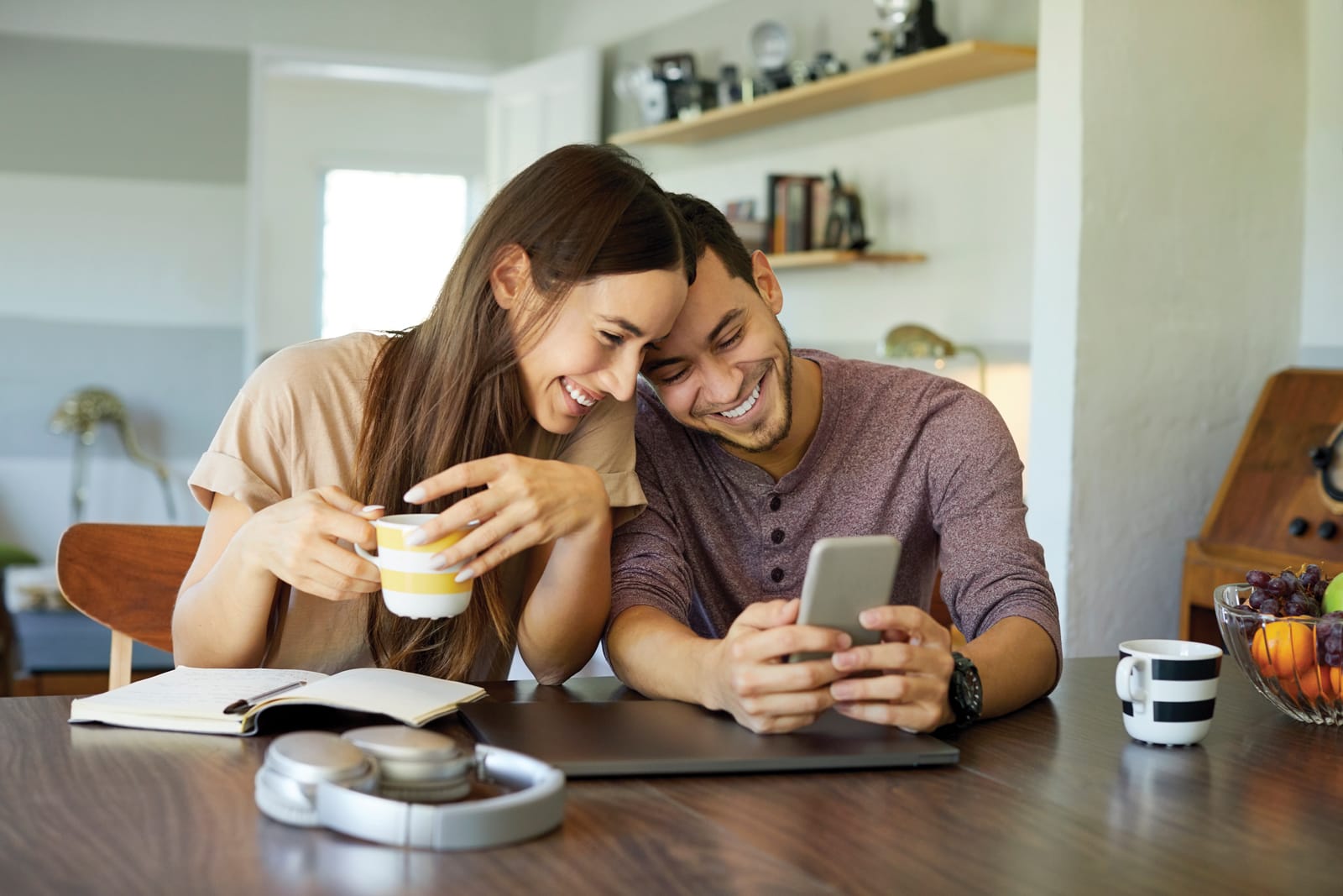 couple smiling looking at phone at home