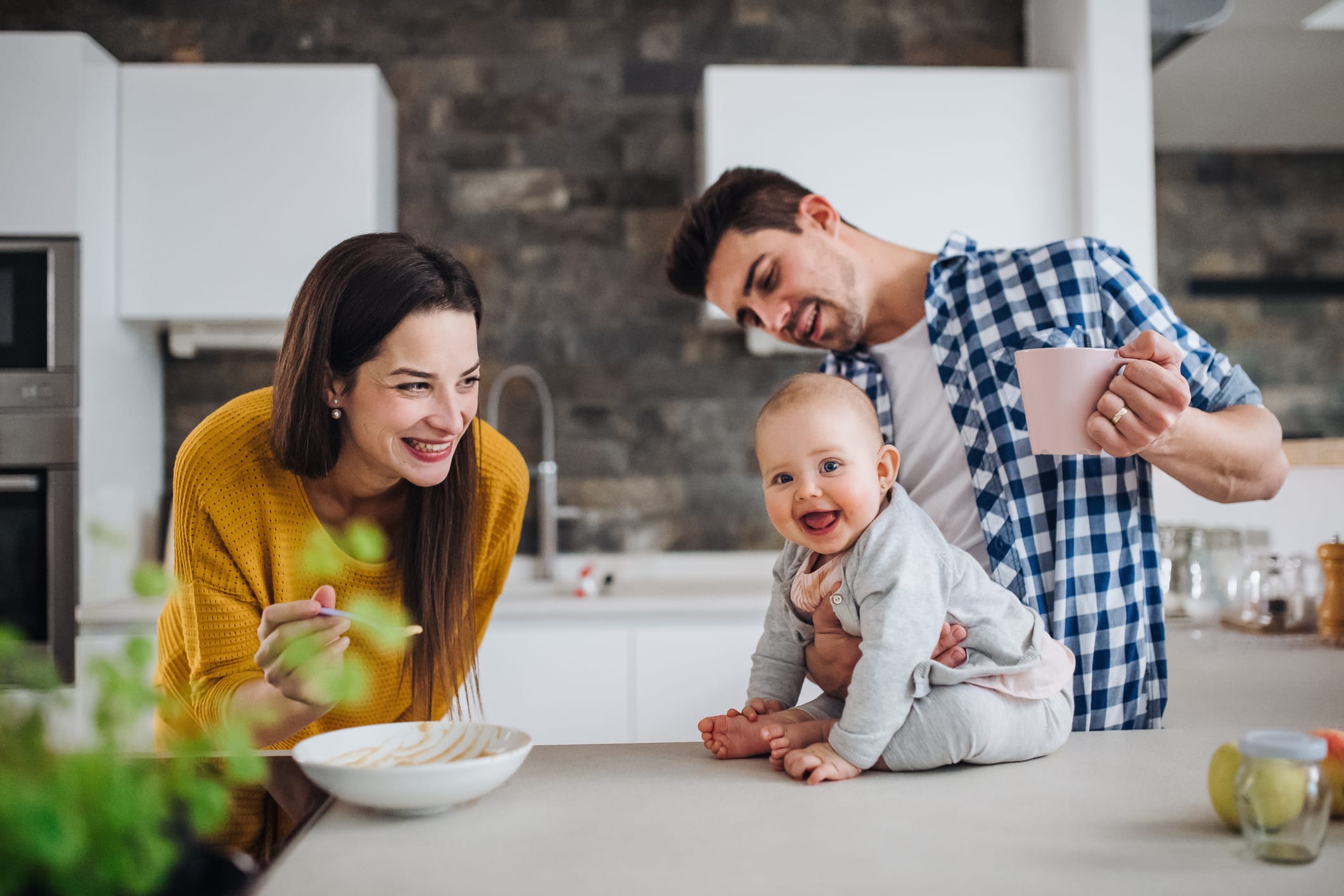 mom dad and baby smiling in the kitchen