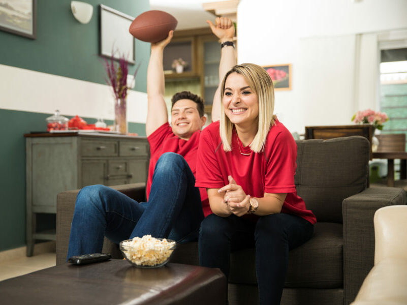 couple watching sports on their couch at home