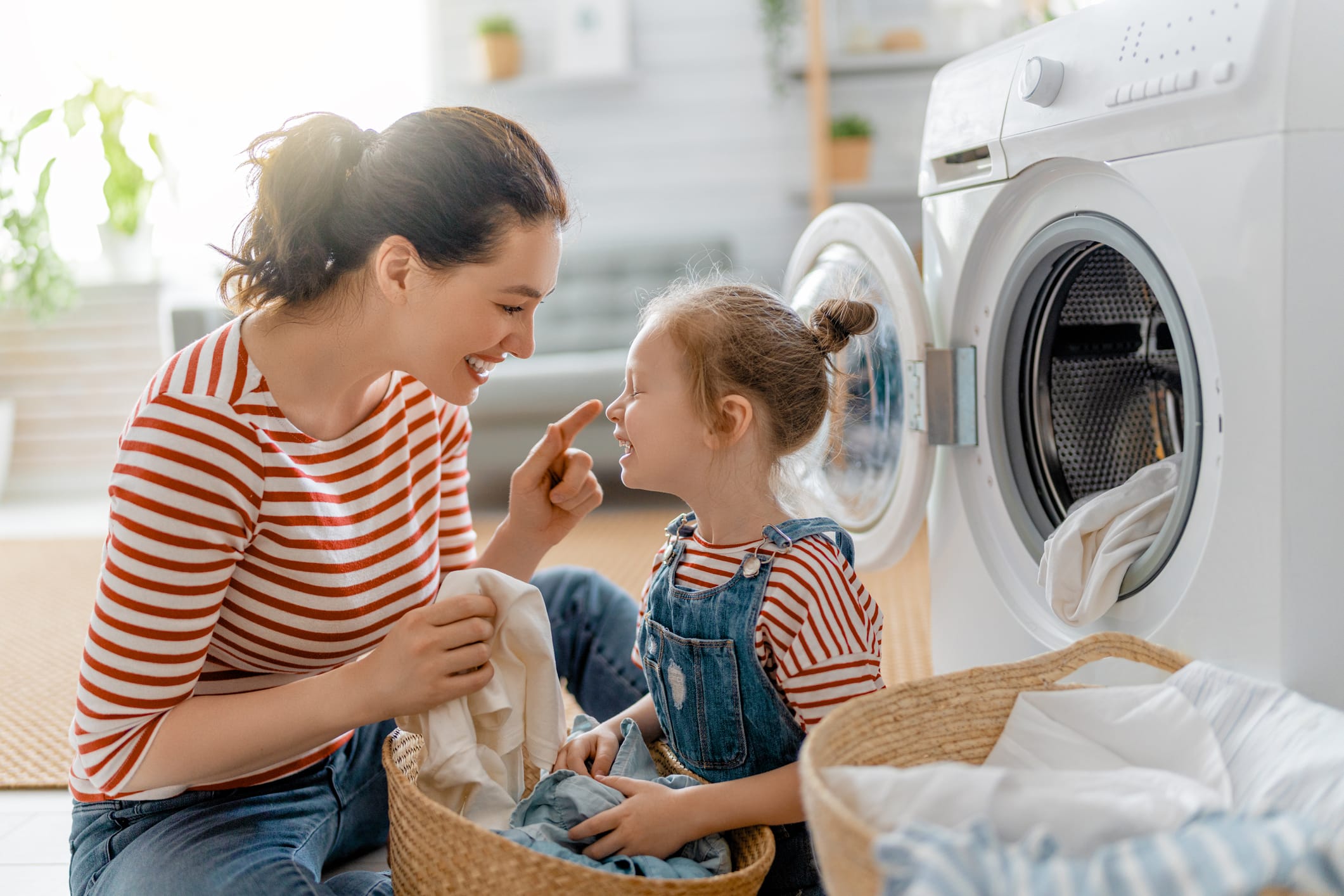 woman folding laundry with young daughter