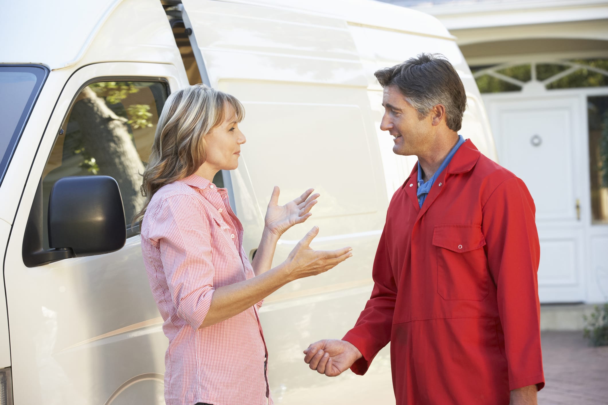 woman talking with home repairman in driveway